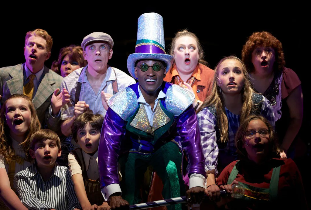 Vernon Bush as Willy Wonka surrounded by the factory company.