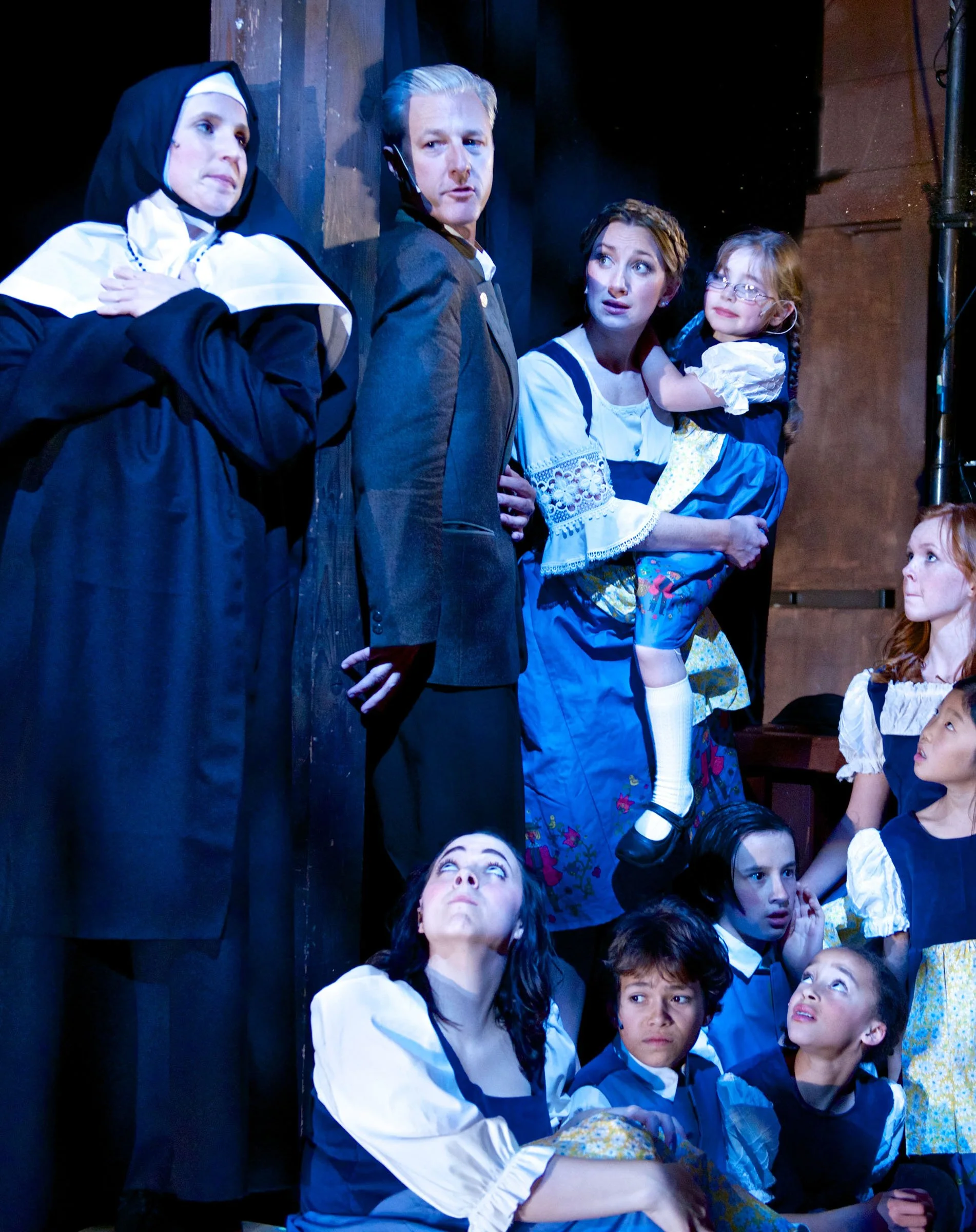 Maria, Captain von Trapp, the children, and the abbey community gathered in a vertical stage tableau.