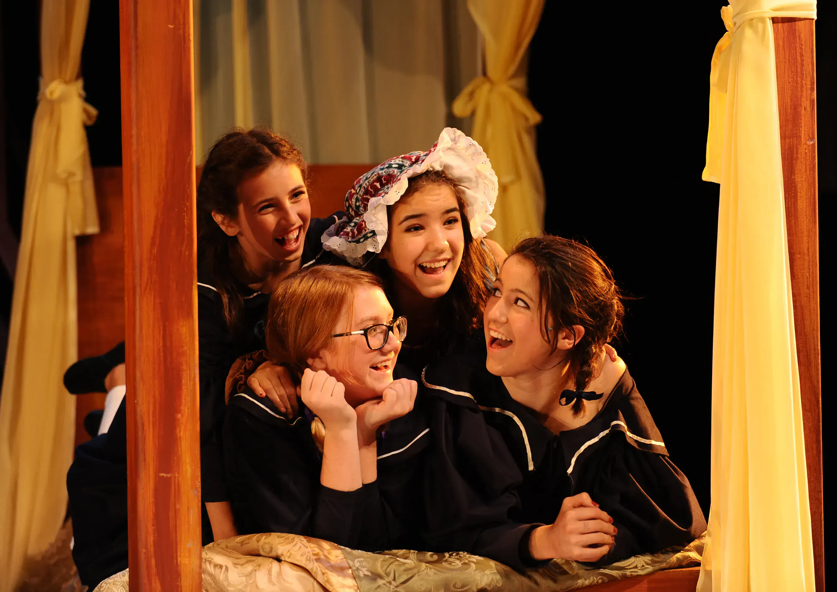 Five young performers share a joyful moment in the dormitory scene from A Little Princess.