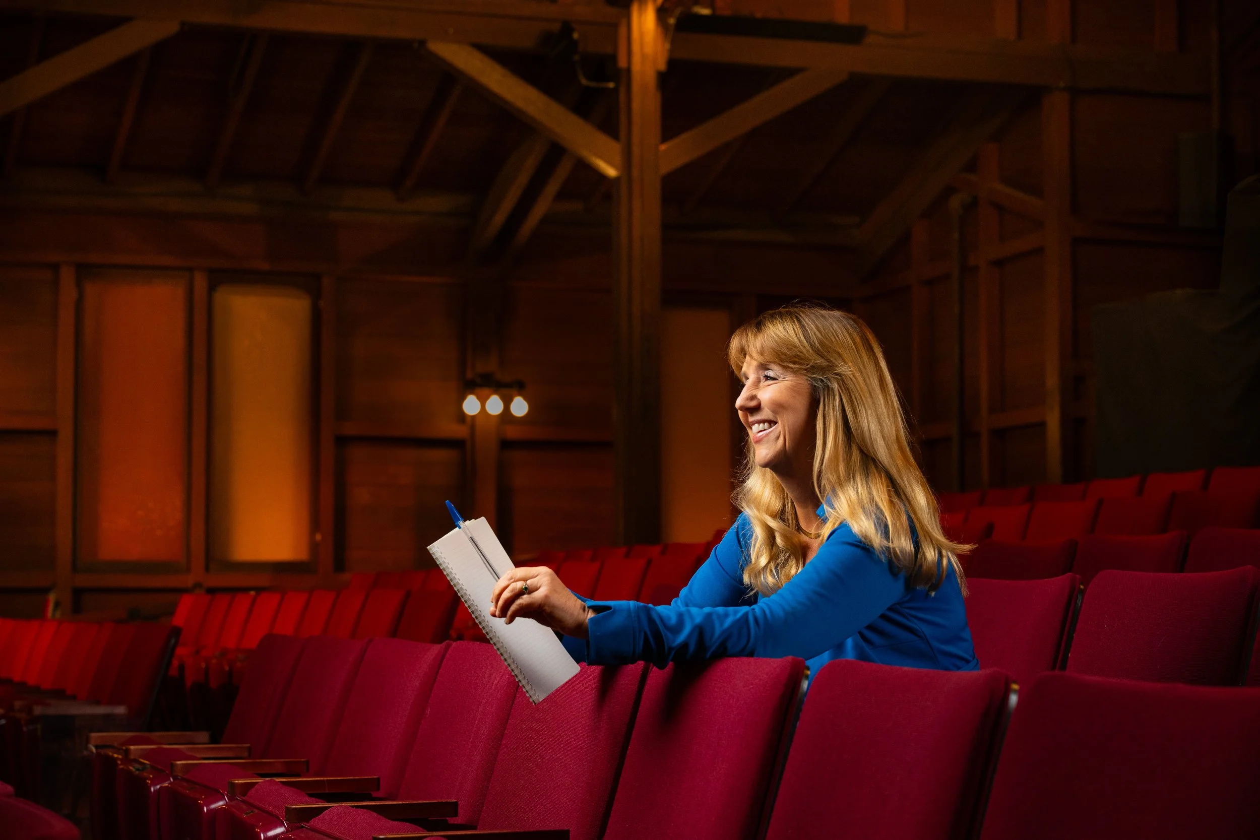 Elizabeth McKoy seated in the historic Julia Morgan Theater with a notebook in hand.