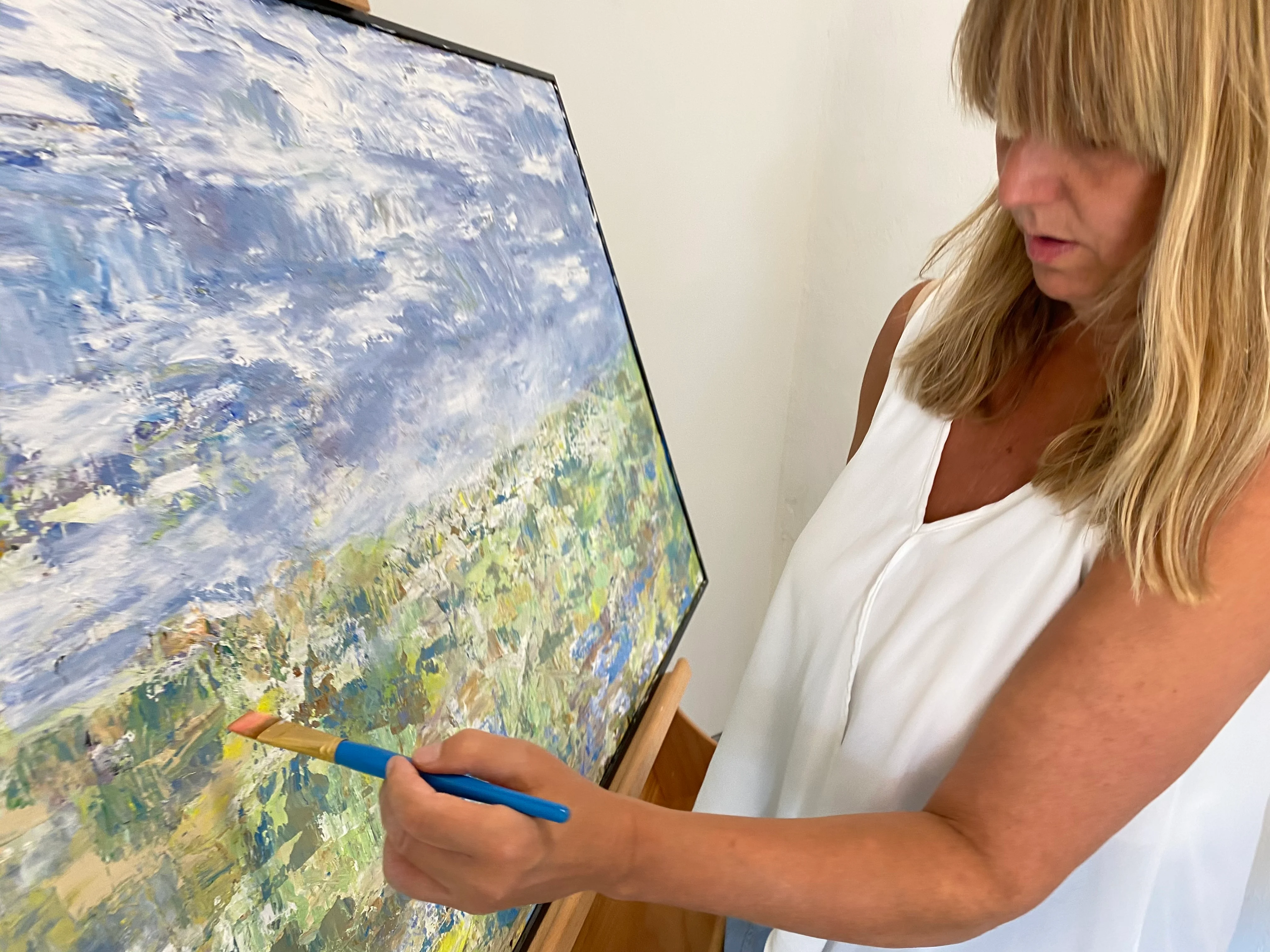 Elizabeth McKoy painting an impressionist landscape at an easel.